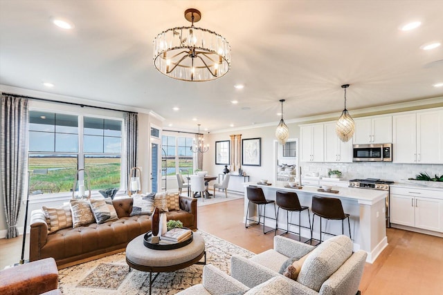 living area featuring ornamental molding, recessed lighting, light wood-style flooring, and a notable chandelier