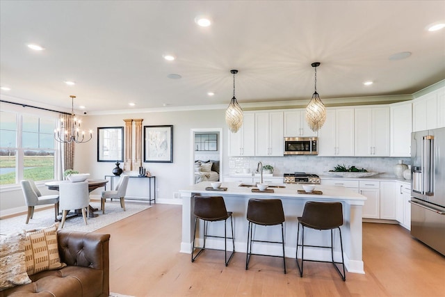 kitchen with a notable chandelier, a sink, light countertops, stainless steel appliances, and decorative backsplash
