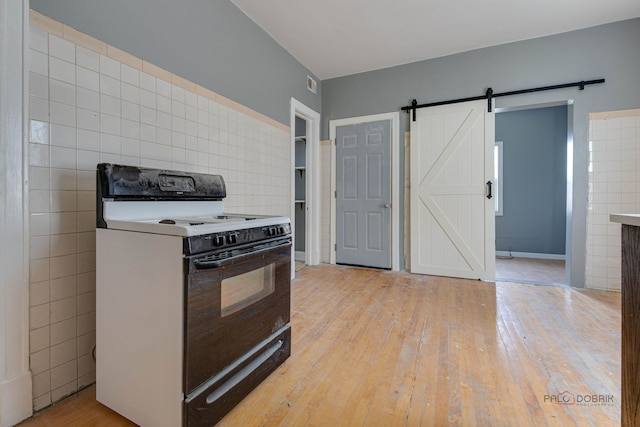 3117 S 53rd Ave, Cicero, IL 60804 - kitchen with electric range, a barn door, light wood-type flooring, and tile walls