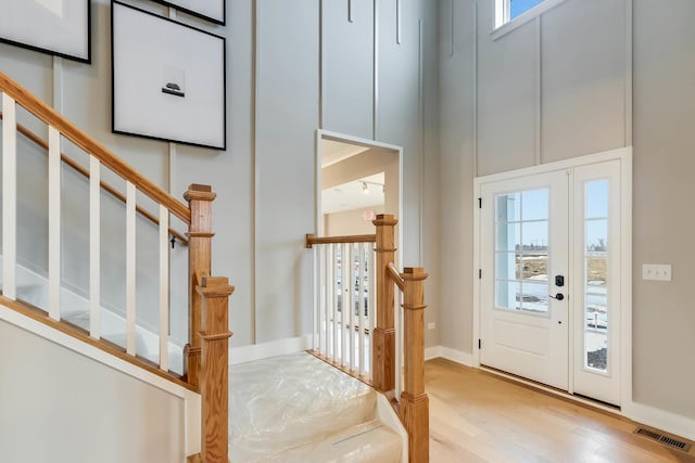 entryway with visible vents, a wealth of natural light, wood finished floors, and stairway