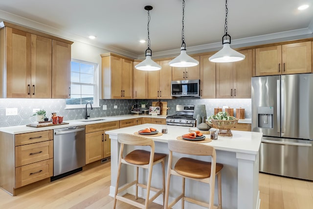 kitchen featuring light wood-style floors, a center island, light countertops, a sink, and appliances with stainless steel finishes