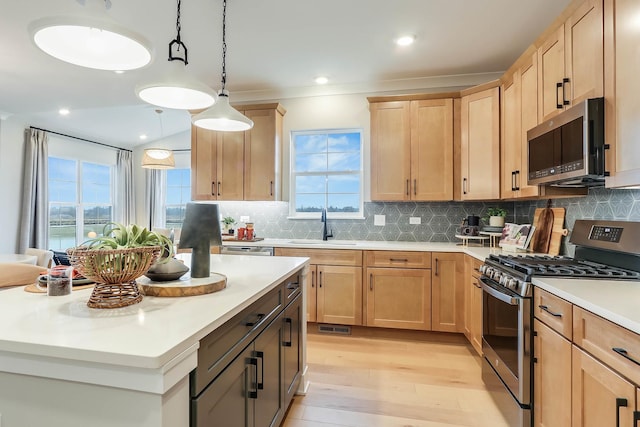 kitchen featuring light brown cabinetry, appliances with stainless steel finishes, a sink, light wood-style floors, and light countertops