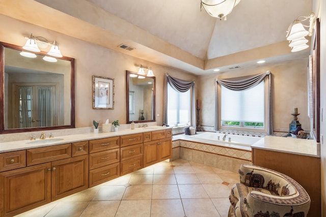full bath featuring tile patterned flooring, a garden tub, double vanity, and lofted ceiling