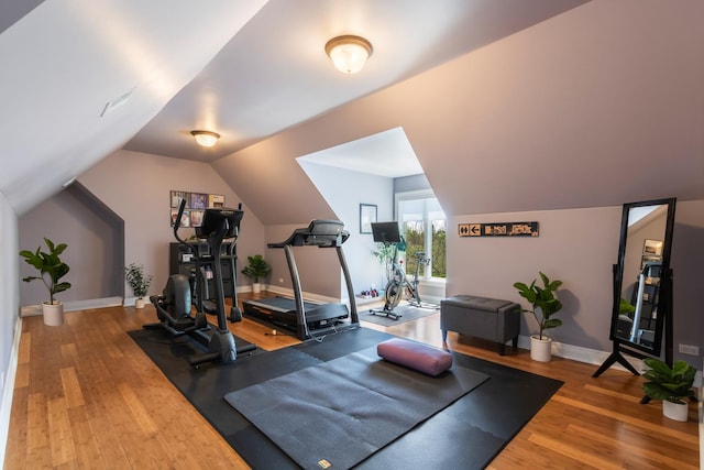 workout area with wood finished floors, vaulted ceiling, and baseboards