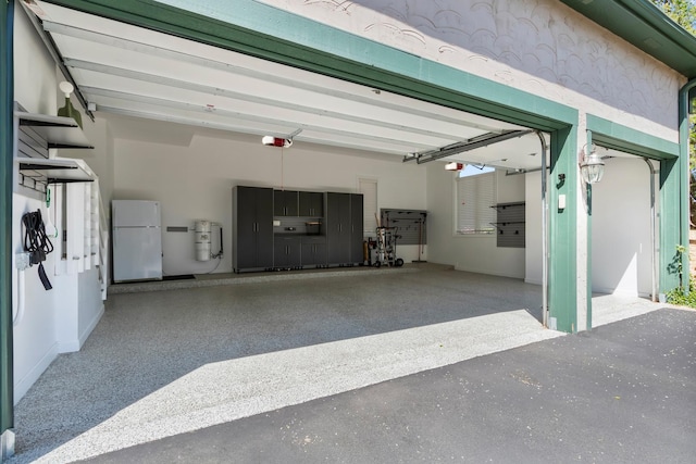 garage with freestanding refrigerator, a garage door opener, asphalt driveway, and a central vacuum unit