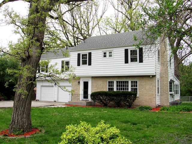 colonial inspired home featuring stone siding, a garage, driveway, and a front yard