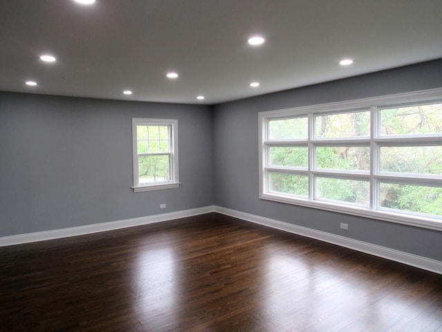 unfurnished room with dark wood-style flooring, recessed lighting, and baseboards