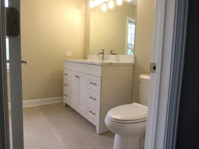 bathroom with toilet, tile patterned flooring, vanity, and baseboards