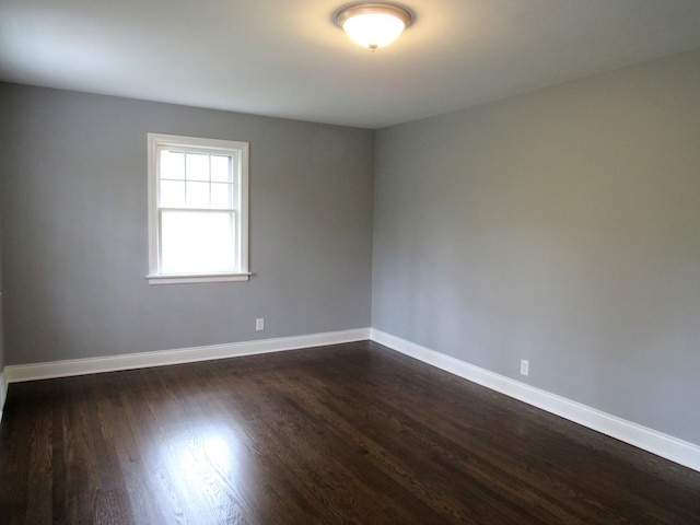 empty room featuring dark wood-style floors and baseboards