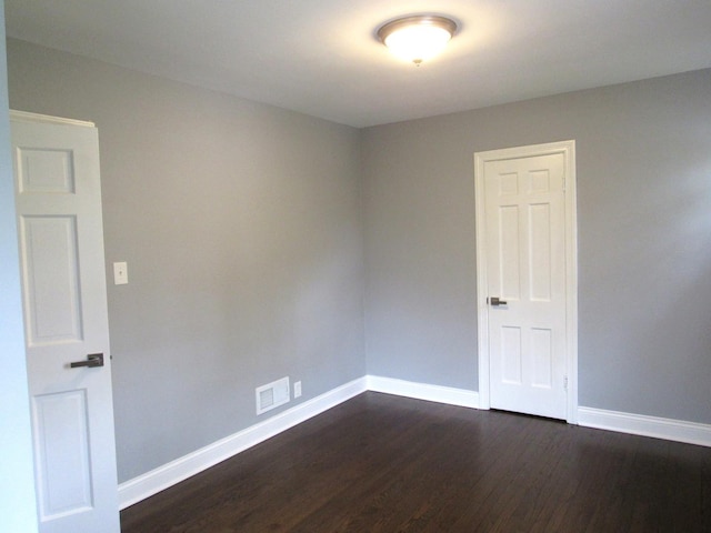 empty room with baseboards and dark wood finished floors