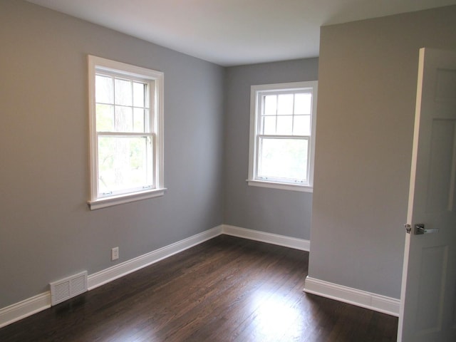 spare room featuring baseboards and dark wood finished floors