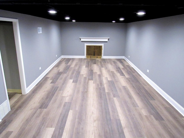 basement with wood finished floors, baseboards, and a fireplace