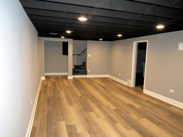 finished below grade area with stairway, wood finished floors, and baseboards