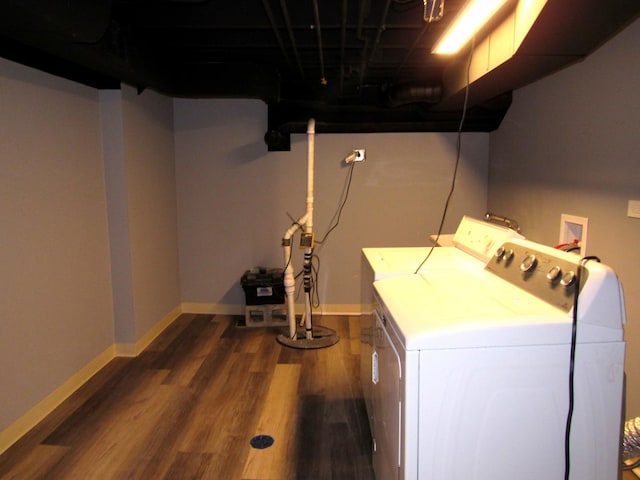 clothes washing area featuring washing machine and dryer, dark wood-type flooring, and baseboards