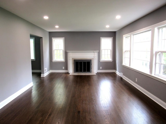 unfurnished living room with a fireplace with flush hearth, dark wood-type flooring, baseboards, and recessed lighting