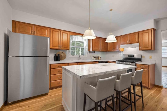 26W266 Tomahawk Dr, Wheaton, IL 60189 - kitchen with appliances with stainless steel finishes, under cabinet range hood, light wood-type flooring, and brown cabinetry