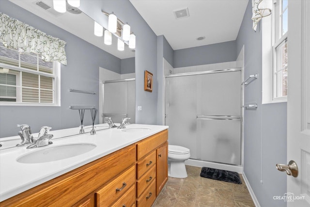 bathroom with a sink, a shower stall, double vanity, and visible vents
