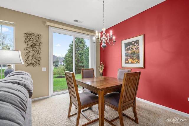 dining area with visible vents, a healthy amount of sunlight, baseboards, light colored carpet, and a notable chandelier