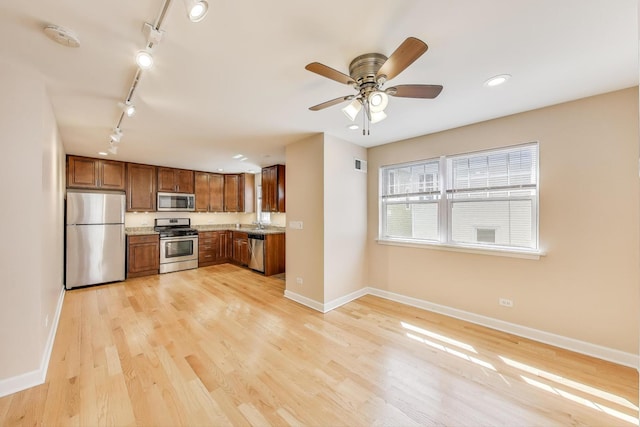 kitchen with rail lighting, brown cabinets, baseboards, and appliances with stainless steel finishes