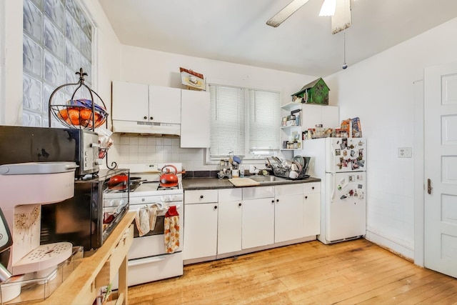 kitchen with light wood-style flooring, under cabinet range hood, white appliances, dark countertops, and white cabinets