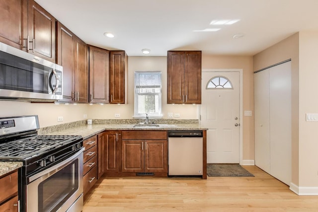 kitchen with light stone countertops, light wood-style flooring, recessed lighting, a sink, and stainless steel appliances