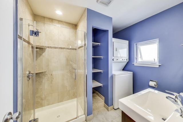 full bathroom featuring marble finish floor, visible vents, a sink, a shower stall, and stacked washing maching and dryer