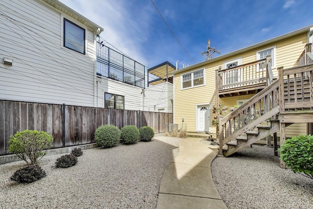 rear view of house featuring stairway, fence, and a wooden deck