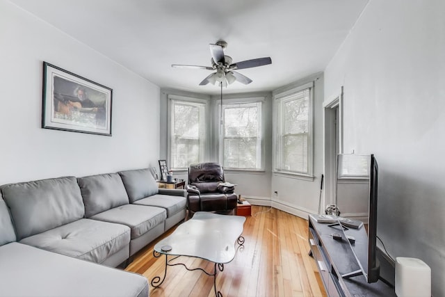 living area featuring a ceiling fan, hardwood / wood-style floors, and baseboards