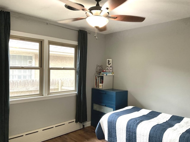 bedroom featuring a ceiling fan, a baseboard heating unit, and wood finished floors