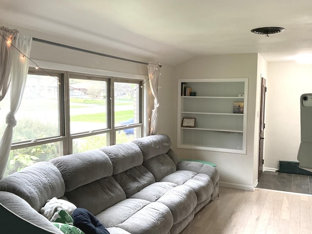 living area with baseboards, wood finished floors, and lofted ceiling