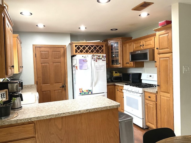 kitchen featuring a peninsula, light countertops, white appliances, and visible vents