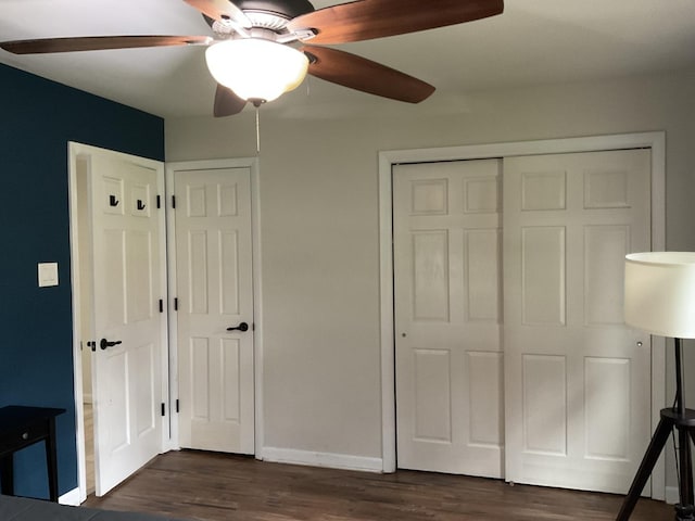 unfurnished bedroom with baseboards, ceiling fan, dark wood-style floors, and a closet