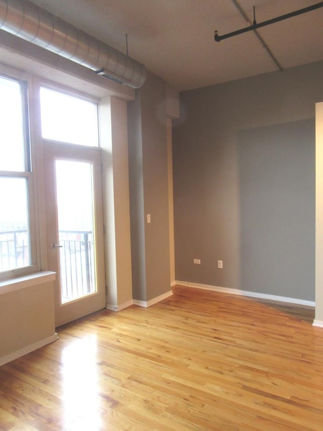 spare room featuring baseboards and light wood-style floors