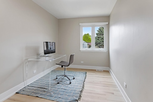 unfurnished office with baseboards, wood finished floors, and visible vents