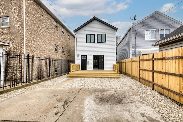 back of property with a fenced backyard and a deck