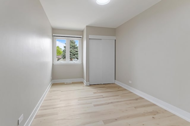 unfurnished bedroom featuring baseboards, a closet, light wood-style flooring, and visible vents