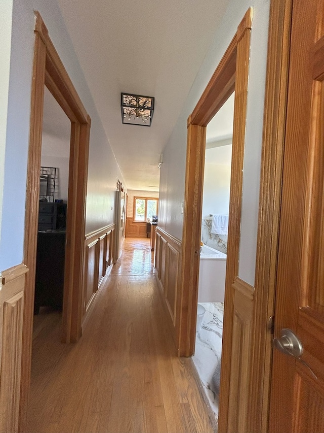 hall featuring light wood-style floors and wainscoting