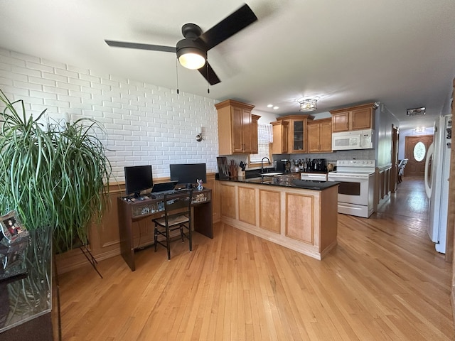 kitchen featuring white appliances, a peninsula, a sink, light wood-style flooring, and a ceiling fan