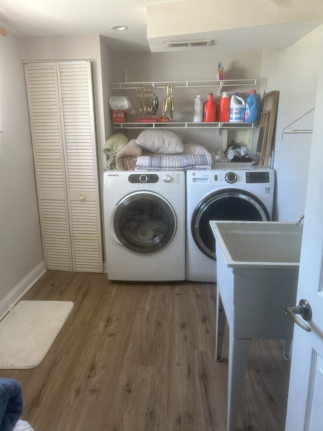 laundry room featuring independent washer and dryer, wood finished floors, and baseboards