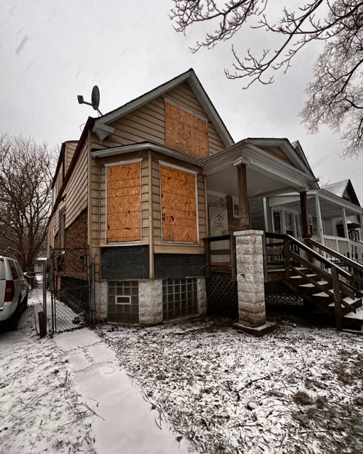 snow covered property with a porch and a gate