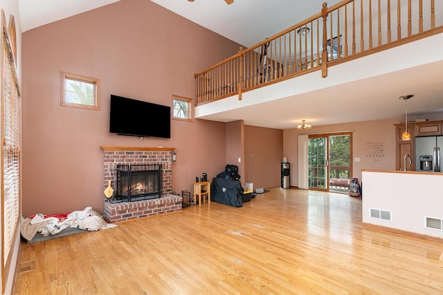 1918 Clement St, Crest Hill, IL 60403 - living room featuring visible vents, a brick fireplace, wood finished floors, ceiling fan, and a high ceiling