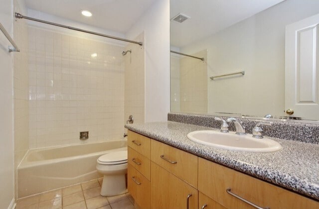 full bathroom with vanity, toilet, tile patterned floors, shower / washtub combination, and visible vents