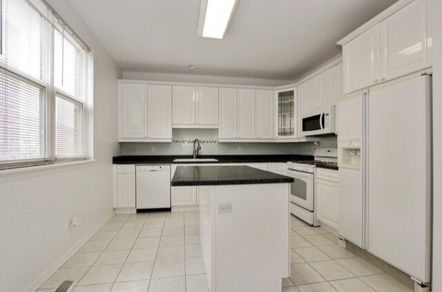 kitchen with white appliances, a kitchen island, a sink, and plenty of natural light
