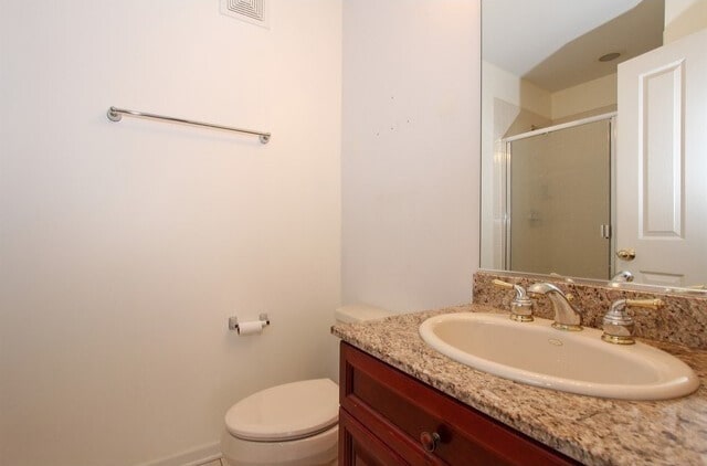 full bathroom with toilet, visible vents, a shower stall, and vanity