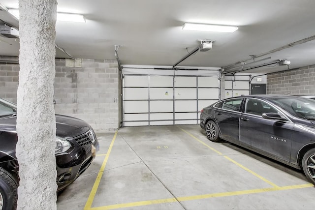 parking garage featuring concrete block wall and a garage door opener