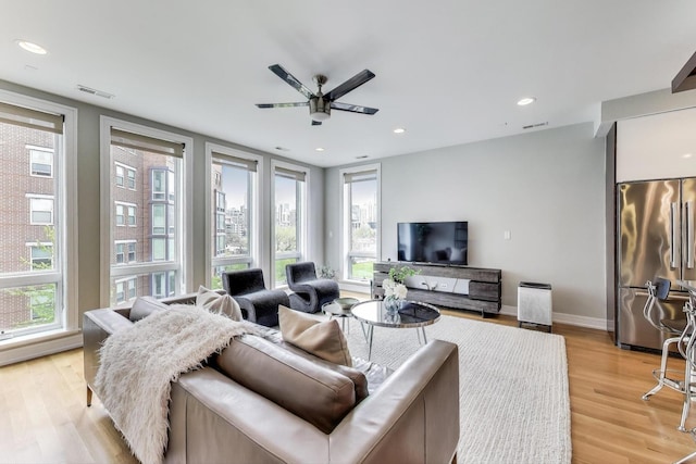living area featuring light wood-style flooring, visible vents, and plenty of natural light