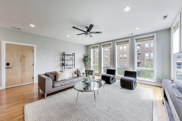 living area with light wood-type flooring, visible vents, and a ceiling fan