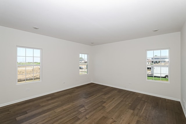 unfurnished room with dark wood-type flooring and baseboards