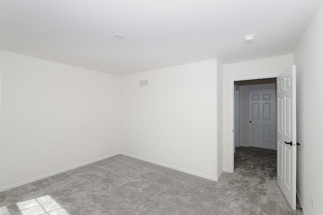 spare room featuring baseboards, visible vents, and light carpet