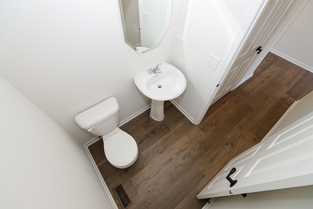 half bathroom with toilet, baseboards, and wood finished floors